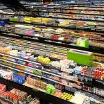 Vista aérea dos corredores de um supermercado, repletos de produtos coloridos.