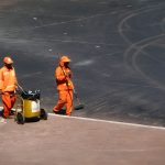 Dois trabalhadores da limpeza urbana usam uniformes laranja durante o trabalho em Brasília.